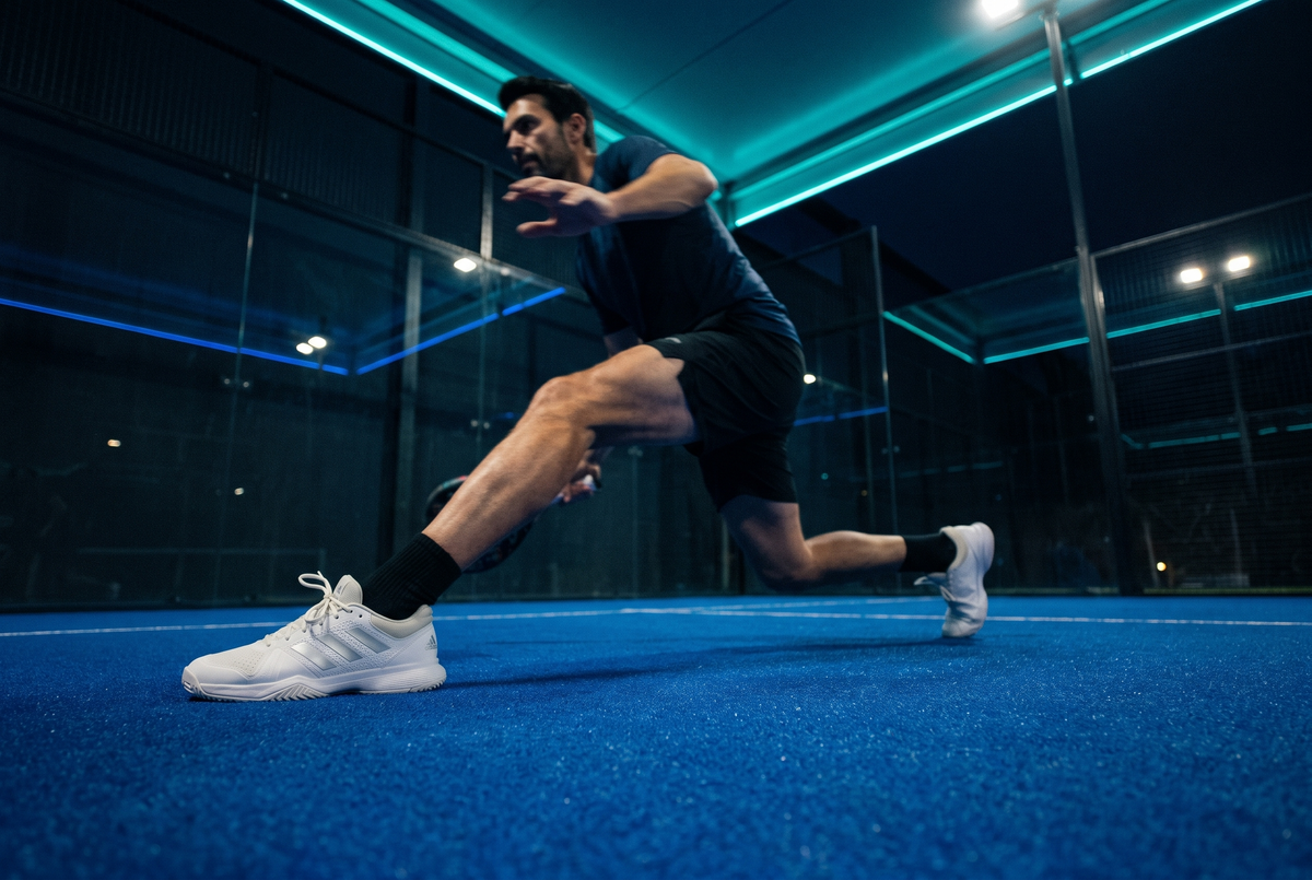 Padel player in split-step on a night court